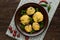 Stuffed mushrooms with salami and mozzarella cheese in a clay bowl on a wooden background.