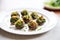 stuffed mushrooms on a white plate, green parsley garnish