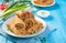 Stuffed pancakes with minced meat with carrots decorated with fresh dill and onions on a blue background.