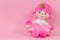 Stuffed soft doll sitting on pink background