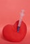 A stuffed toy heart with a syringe stuck in it