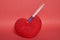 A stuffed toy heart with a syringe stuck in it