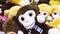 A stuffed toy monkey with big black eyes lying with a bunch of other stuffed toys.