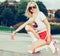 A stunner summer closeup portrait of young happy woman posing in a vintage roller skates, sunglasses, T-shirt, shorts posing