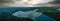 Stunning aerial panoramic shot of the still blue waters of the lake with blue sky and clouds reflecting off the water