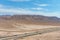 A stunning aerial shot of majestic mountain ranges in a vast desert land with powerful clouds with freeways