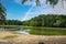 A stunning aerial shot of the silky green waters of the lake with vast miles of lush green trees and blue sky and clouds and birds