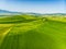 Stunning aerial view of green fields and farmlands with small villages on the horizon. Rural landscape of rolling hills, curved