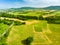 Stunning aerial view of green fields and farmlands. Summer rural landscape of rolling hills, curved roads and cypresses of Tuscany