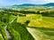 Stunning aerial view of green fields and farmlands. Summer rural landscape of rolling hills, curved roads and cypresses of Tuscany