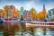Stunning autumn cityscape of Amsterdam. Famous Dutch channels and excursion boat. Colorful morning landscape in Netherlands, Europ