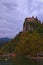 Stunning autumn landscape view of ancient Bled Castle on the top of the cliff. Cloudy sky in the background.