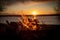 Stunning beachside scene with a bonfire blazing in the foreground at sunset