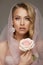 Stunning blonde model in pink veil. natural make-up wearing pink veil and holding fragile pink rose.