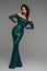 Stunning brunette of model beauty, showcasing a green evening dress