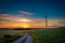 Stunning colorful dusk over country road and wind turbines