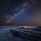 Stunning composite landscape image of Mily Way core over sea rocks and cliffs with long exposure tide on beach