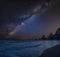 Stunning composite landscape image of Mily Way core over sea rocks and cliffs with long exposure tide on beach