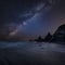 Stunning composite landscape image of Mily Way core over sea rocks and cliffs with long exposure tide on beach