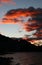 Stunning deep red clouds like fiery fire in sky above water at sunrise