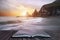 Stunning dramatic sunrise over beach with jagged rocks coastline