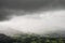 Stunning epic landscape image across Derwentwater valley with falling rain drifting across the mountains causing pokcets of light