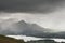 Stunning epic landscape image across Derwentwater valley with falling rain drifting across the mountains causing pokcets of light