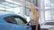 Stunning female customer smiling to the camera, examining new car at dealership