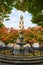 Stunning fountain surrounded by fall leaves in city with Christian Church steeple behind in New York City