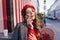 Stunning french woman with long brown hair talking on phone in outdoor cafe. Portrait of resting curly girl in red beret