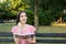 Stunning girl on the bench thinking with a book and a pen by her head in the park