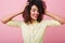 Stunning girl with dark-brown curls having fun during studio photoshoot. Indoor photo of pleased black woman wears