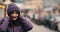 Stunning girl in purple winter hat and coat with bright make up walking in the street.