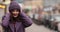 Stunning girl in purple winter hat and coat with bright make up walking in the street.
