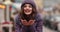 Stunning girl in purple winter hat and coat with bright make up walking in the street.