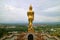 Stunning gold colored Buddha image in walking posture facing the town of Nan, Wat Phra That Khao Noi temple, Thailand