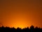 Stunning golden gradation of sunset sky over the silhouette of countryside forest