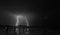 Stunning grayscale shot of a distant lightning strike from a pier