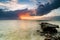 stunning image during sunset at the coastline. abandon concrete structure on the water, dramatic dark clouds with sunlight