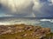 Stunning Irish seascape with rough stone coast line and powerful Atlantic ocean and colorful rainbow. Kilkee area, Ireland.