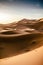 Stunning landscape of large sand dunes in the desert of Erg Chebbi. Sunrise view of the desert with camel driver walking