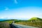 The stunning landscape of the way in a rural area in New Zealand. Gravel road among green grassland with blue sky. I