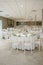 Stunning large hall adorned with white tables, set up for a beautiful wedding reception