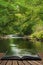 Stunning lush green riverbank with river flowing slowly past calm landscape coming out of pages of open story book