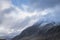 Stunning moody dramatic Winter landscape image of snowcapped Tryfan mountain in Snowdonia with stormy weather brooding overhead