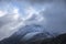 Stunning moody dramatic Winter landscape image of snowcapped Tryfan mountain in Snowdonia with stormy weather brooding overhead