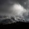 Stunning moody dramatic Winter landscape image of snowcapped Tryfan mountain in Snowdonia with stormy weather brooding overhead