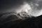 Stunning moody dramatic Winter landscape image of snowcapped Tryfan mountain in Snowdonia with stormy weather brooding overhead