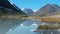 Stunning natural scenery. Mountain lake with white water. Snow peaks are reflected in water. Slow motion