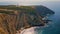 Stunning ocean cliffs summer evening aerial. Lighthouse standing on coastal rock